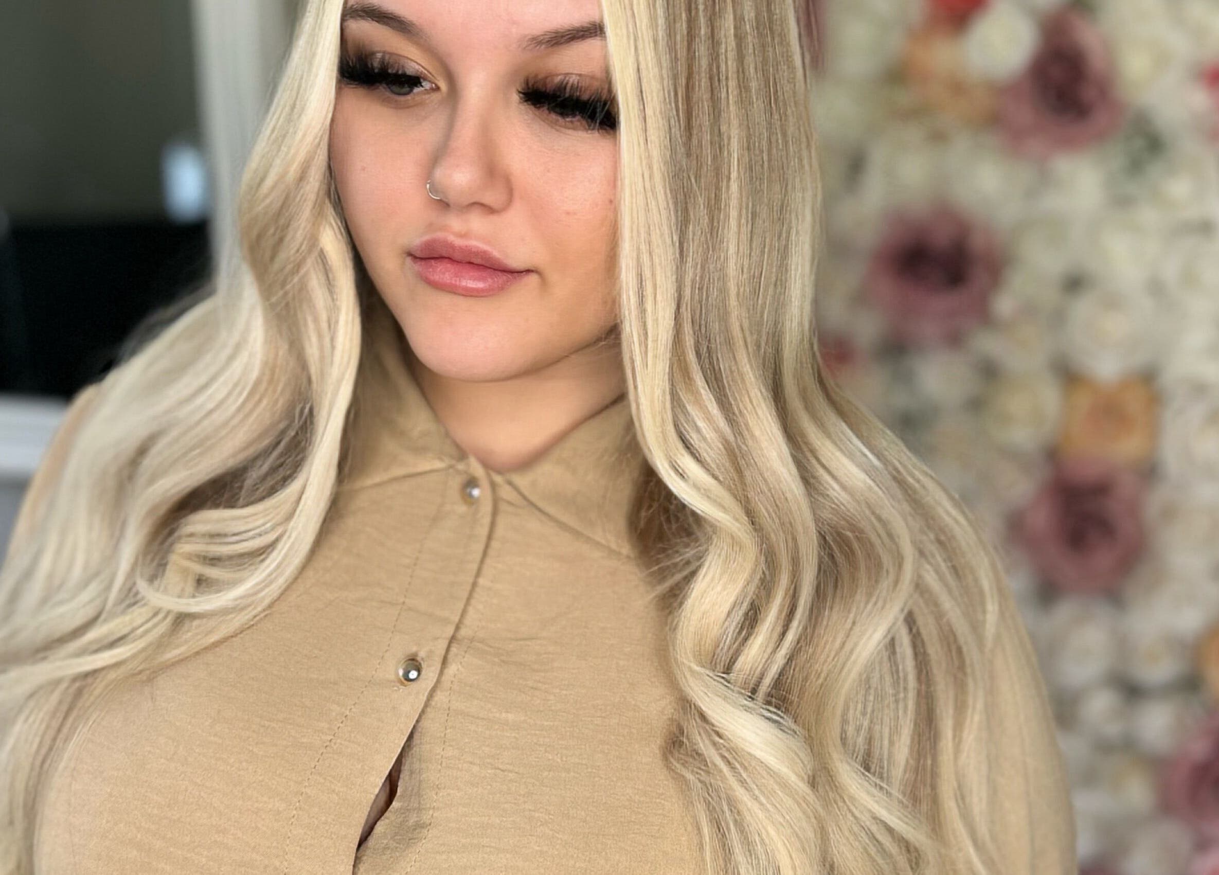 Blonde woman with styled hair at Ksk Hair Academy, Lydney, England, GB, against floral backdrop.