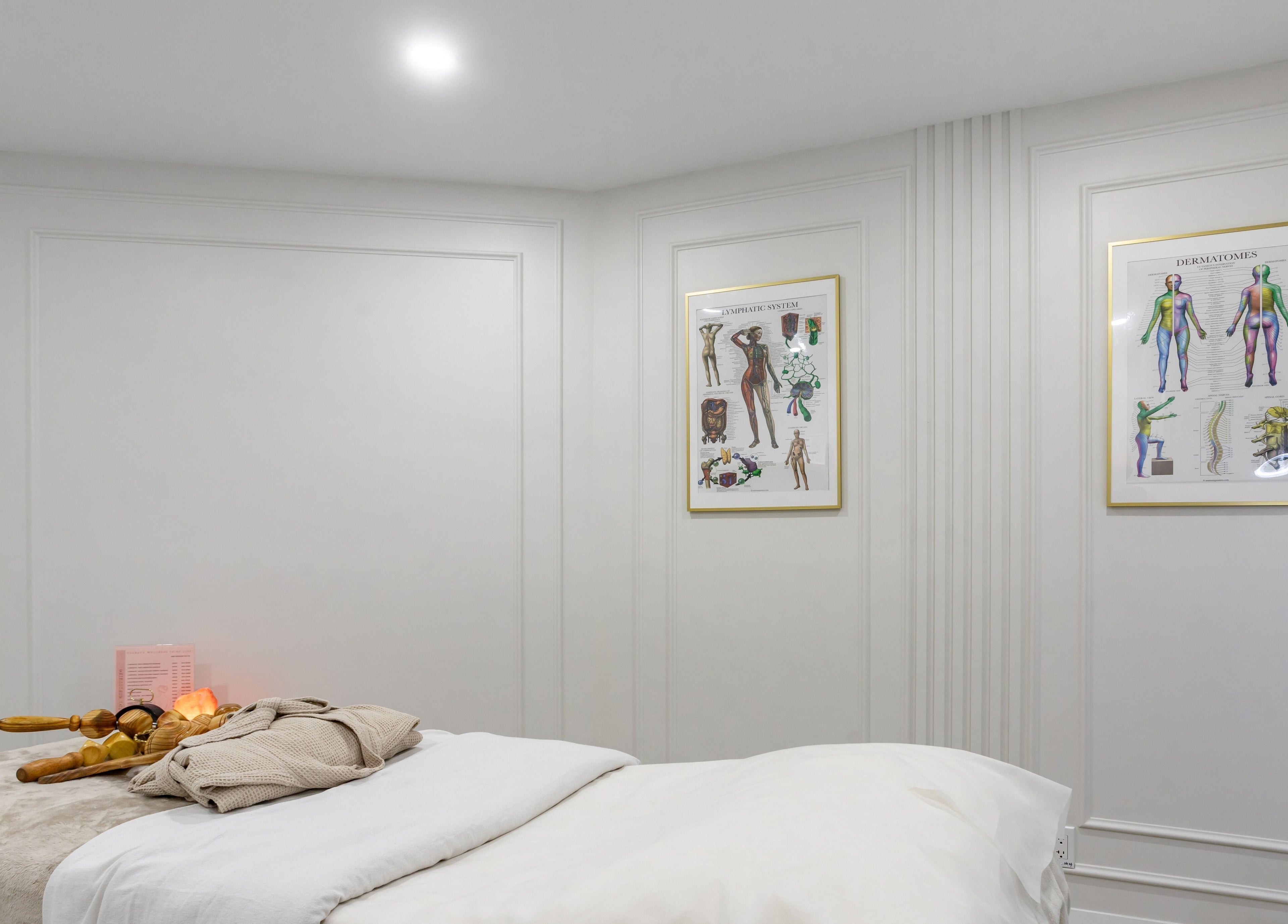 Tranquil therapy room at Aura Wellness, Vaughan, Ontario, CA with massage table and anatomical charts.