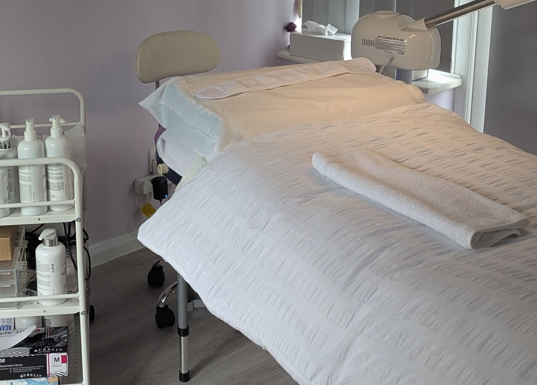 A tranquil treatment room at The Amethyst Room Rayleigh, Rayleigh, England, GB, featuring a prepared massage bed.