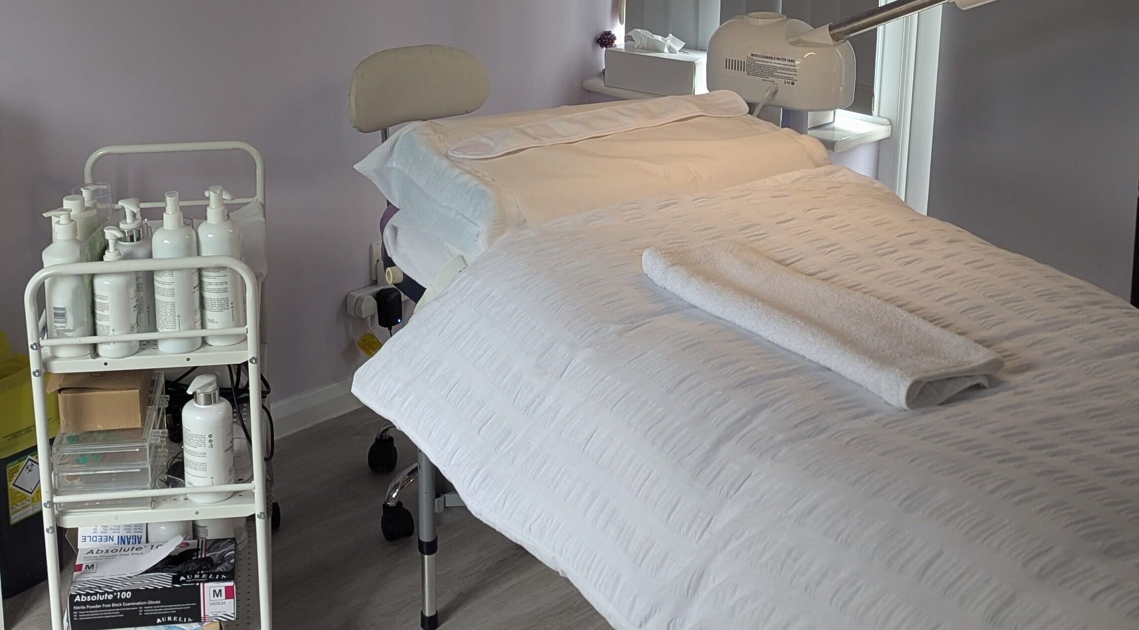 A tranquil treatment room at The Amethyst Room Rayleigh, Rayleigh, England, GB, featuring a prepared massage bed.