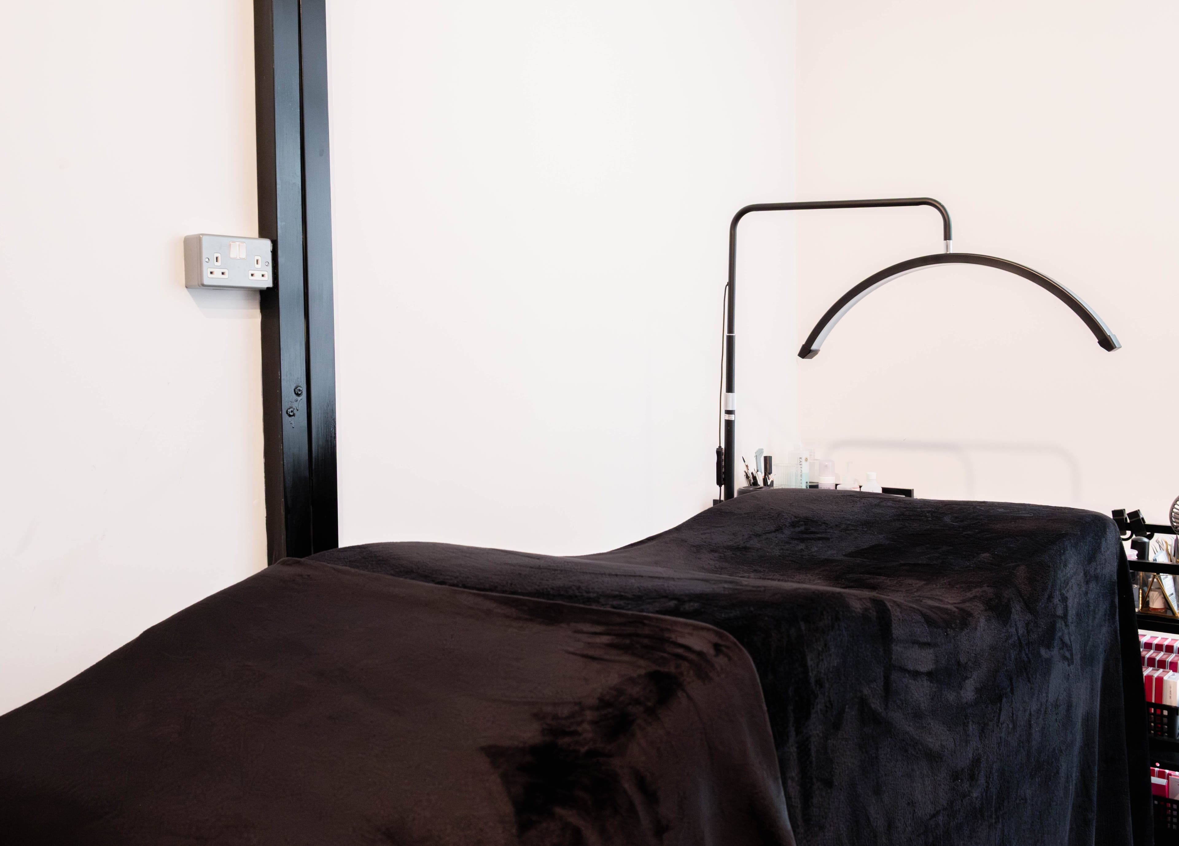 Relaxing treatment room at AV Lashes London in London, England, GB, featuring a cozy black therapy bed.
