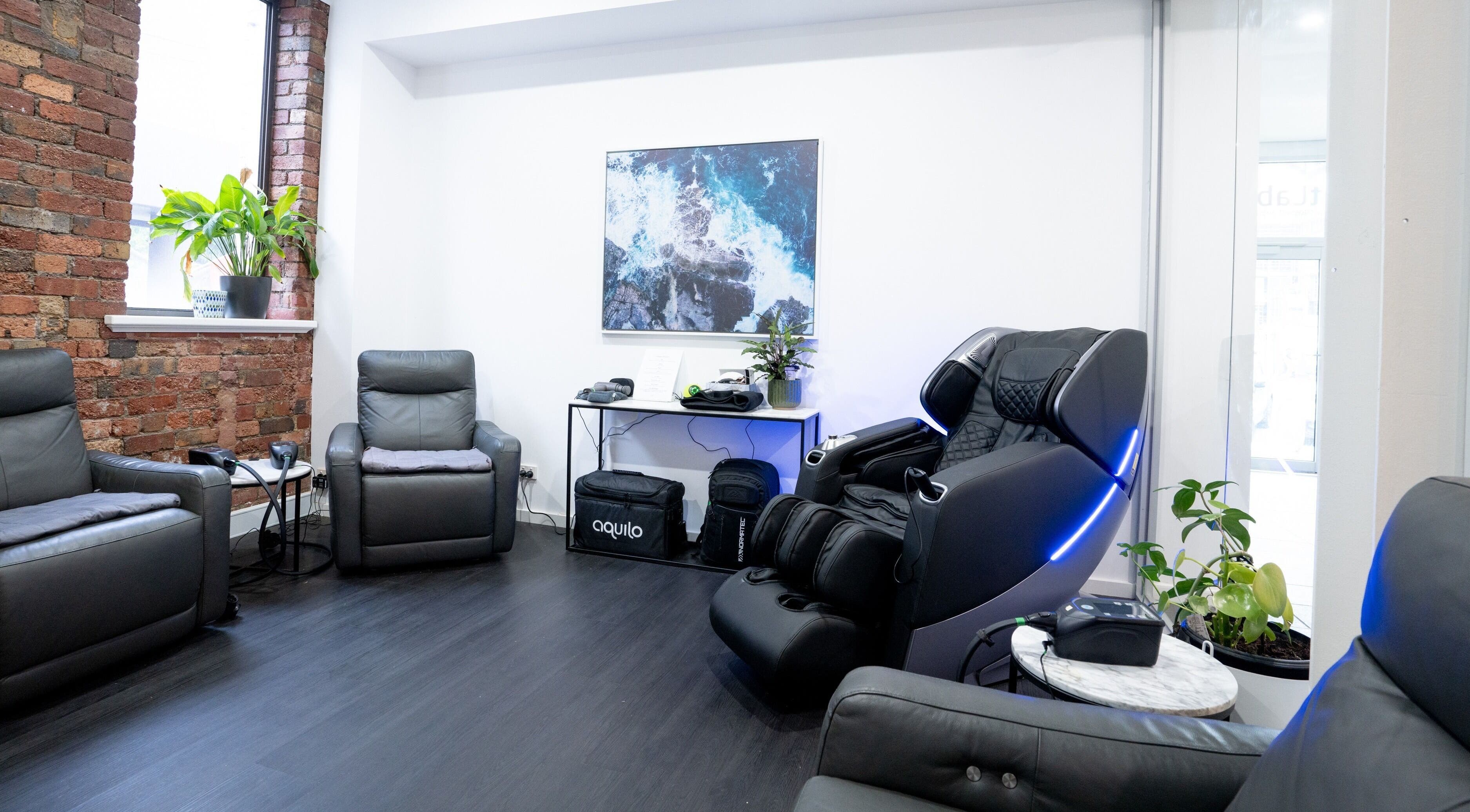 Comfortable massage chairs at Gentle Recovery, South Melbourne, VIC, AU, with modern decor and brick walls.
