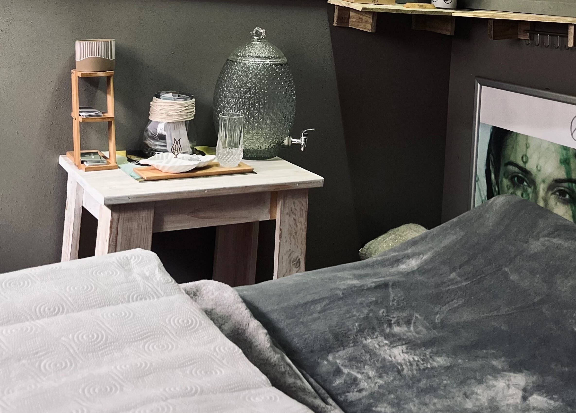 Relaxing spa room at AfriU Refinery in George, Western Cape, ZA featuring cozy blanket and water dispenser.