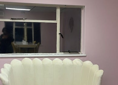 Cozy lounge with white scallop chair at Melanin Lash Bar SA, Sandton, Gauteng, ZA, pink walls, and window.