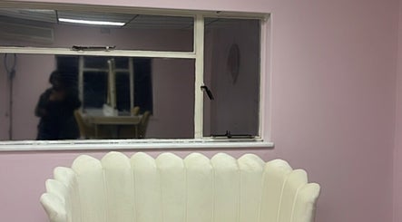 Cozy lounge with white scallop chair at Melanin Lash Bar SA, Sandton, Gauteng, ZA, pink walls, and window.