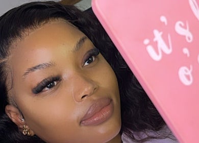 Client with fresh lashes at Melanin Lash Bar SA, Sandton, Gauteng, ZA, holding a pink mirror.