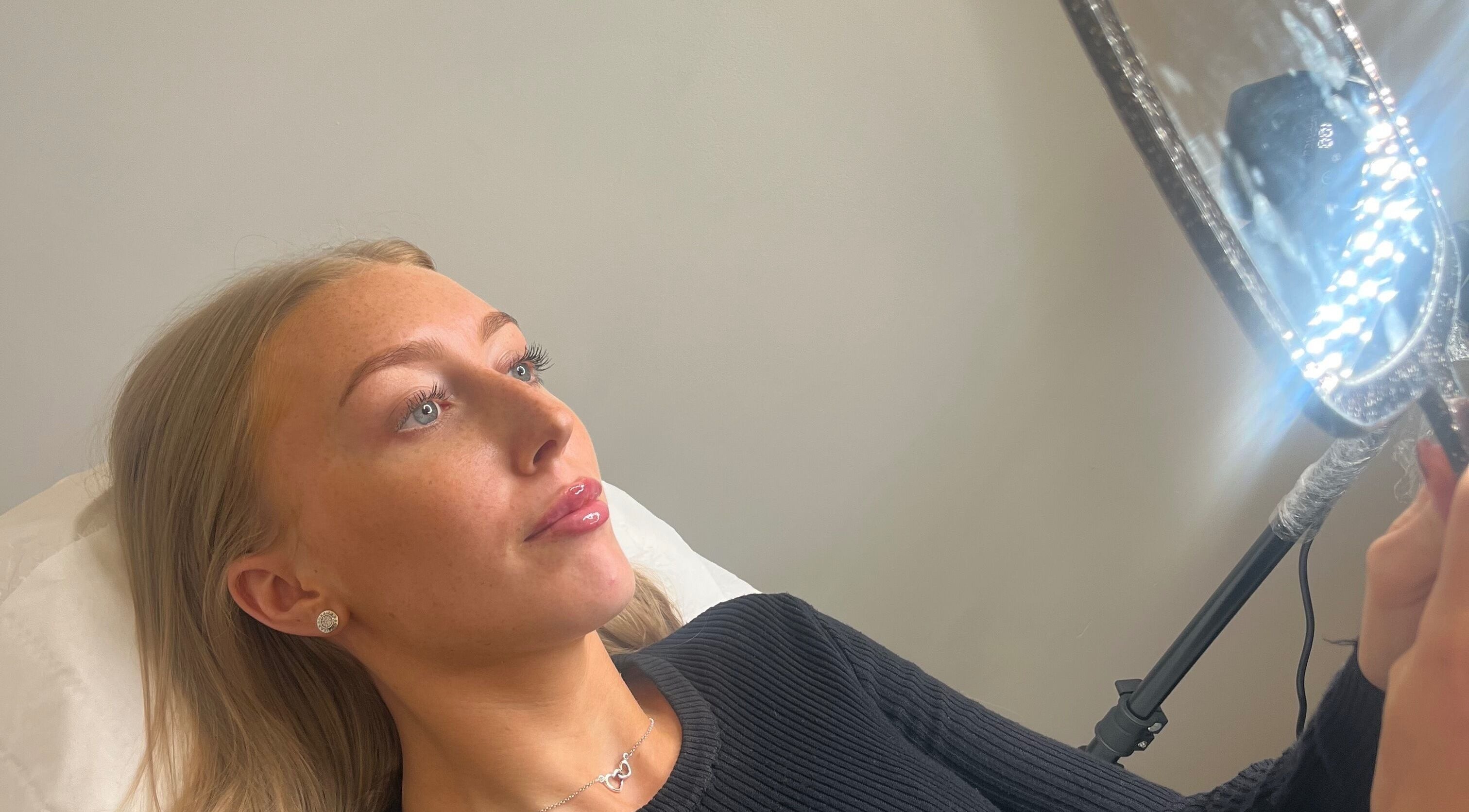 Client admiring results in a mirror at Farr Beyond Aesthetics, Plymouth, England, GB.