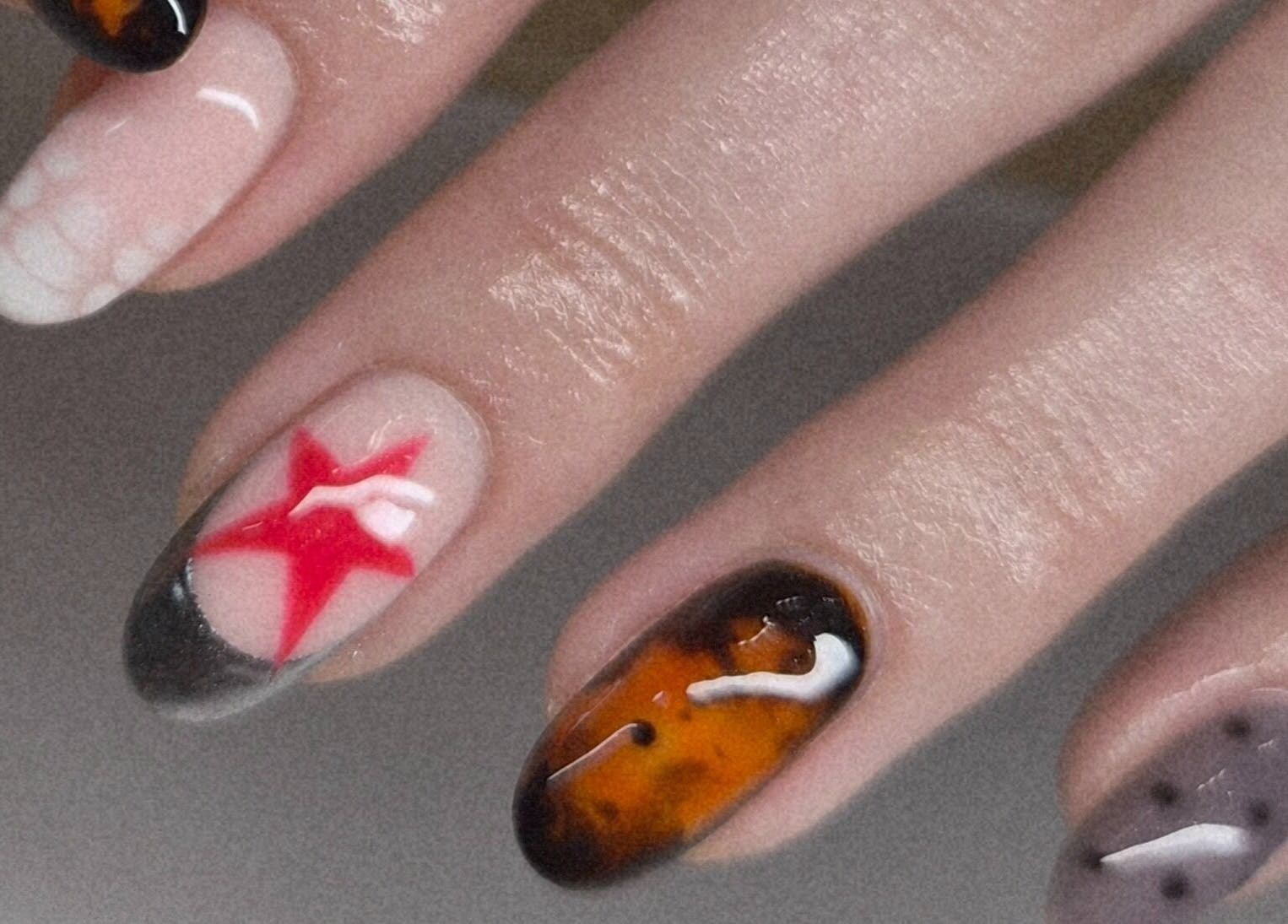Art Thou Nails in Manchester, England, GB showcases unique nail art with vibrant red, amber, and grey designs.