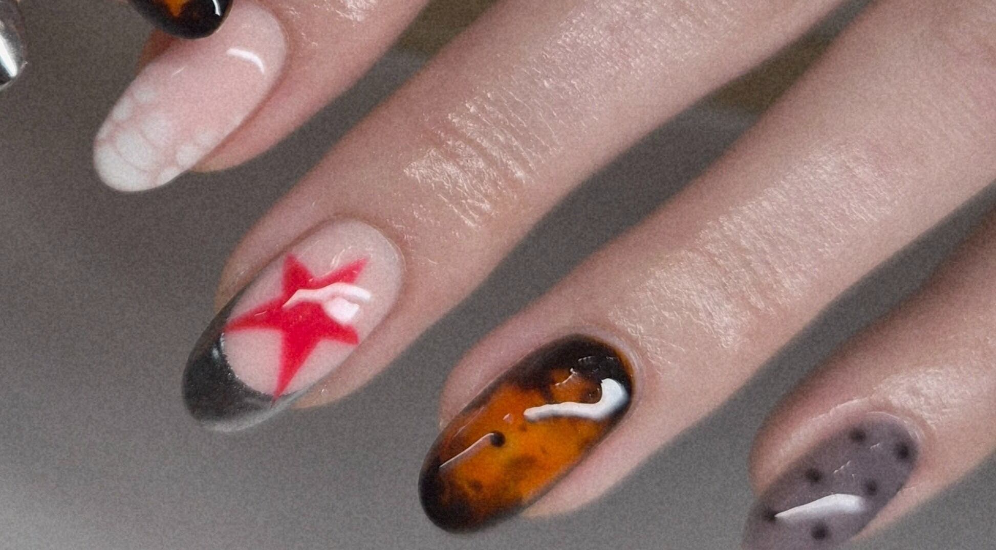 Art Thou Nails in Manchester, England, GB showcases unique nail art with vibrant red, amber, and grey designs.