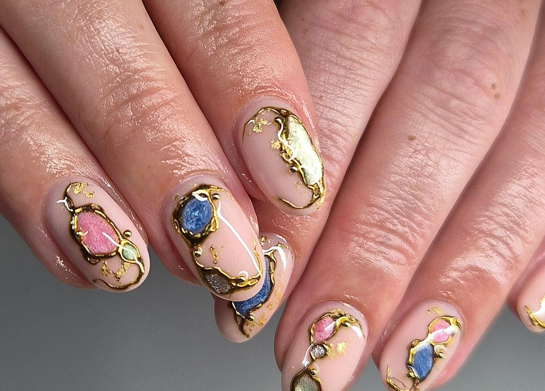 Elegant nail art at Art Thou Nails, Manchester, England, GB showcasing intricate gold and gemstone designs.