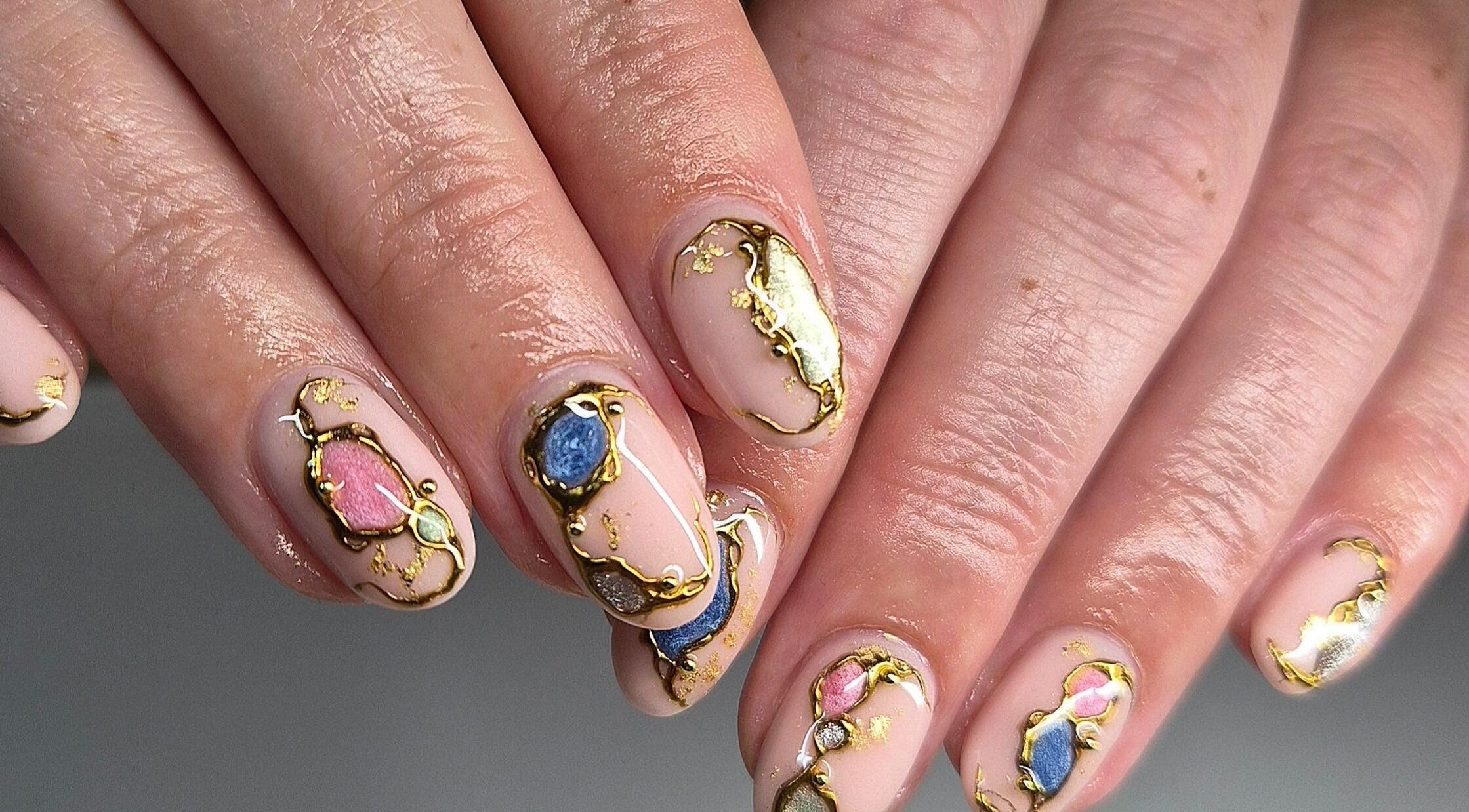 Elegant nail art at Art Thou Nails, Manchester, England, GB showcasing intricate gold and gemstone designs.