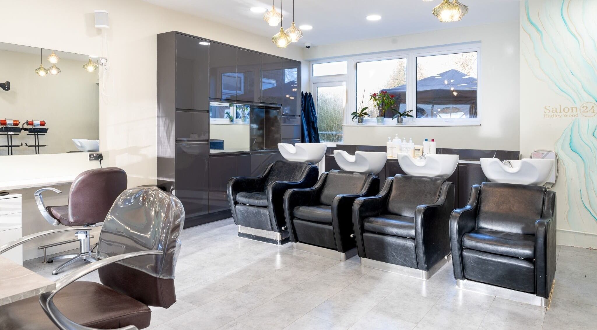 Modern salon interior at Salon 24 Hadley Wood, Barnet, England, GB featuring sleek washing stations.