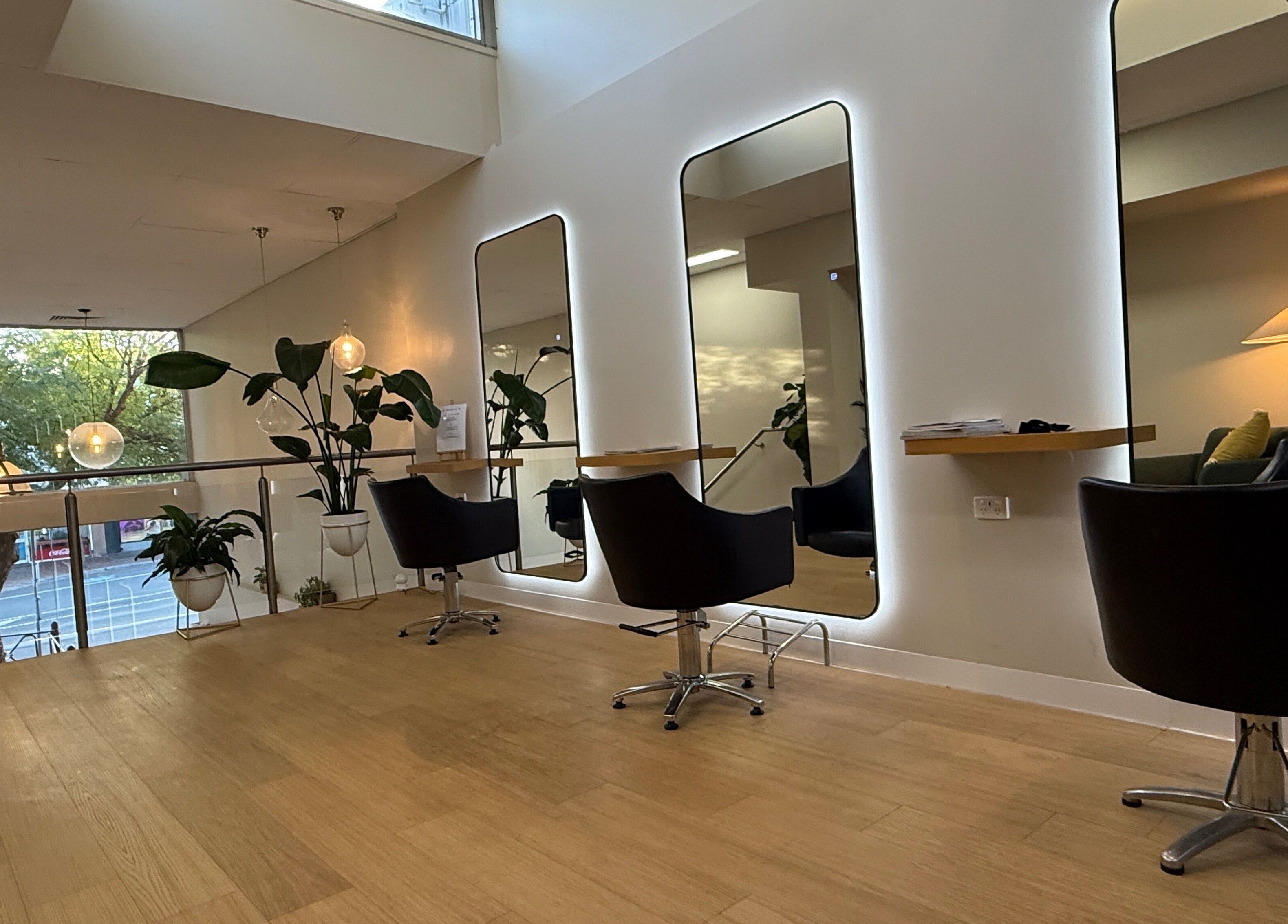 Modern styling area at Biba Croydon in Melbourne, Victoria, AU, featuring sleek black chairs and large mirrors.