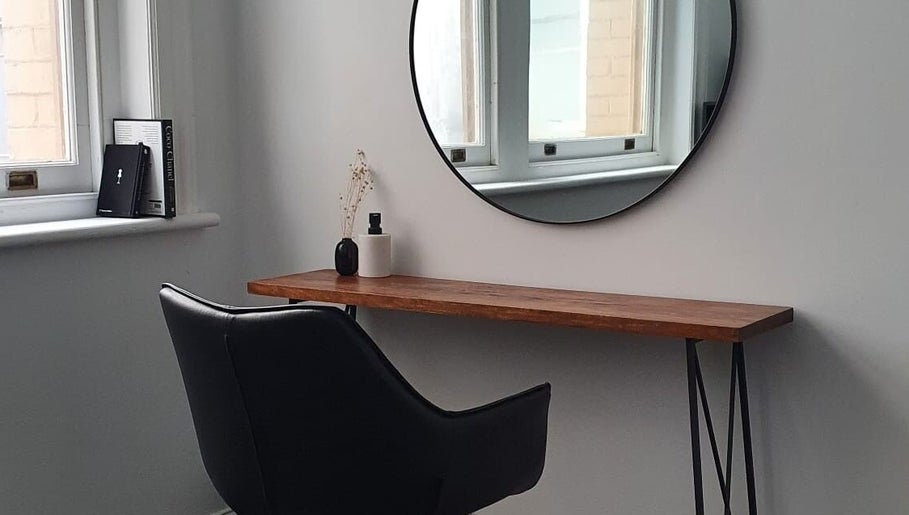 Chic salon interior with a black chair and round mirror at Jacqueline Louise Hair, Sydney, New South Wales, AU.