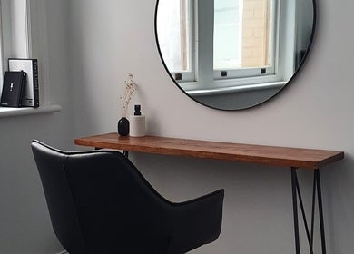 Chic salon interior with a black chair and round mirror at Jacqueline Louise Hair, Sydney, New South Wales, AU.