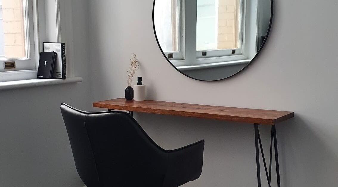 Chic salon interior with a black chair and round mirror at Jacqueline Louise Hair, Sydney, New South Wales, AU.