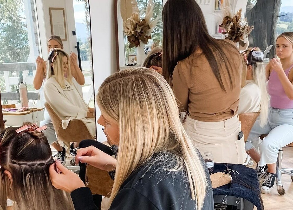 Stylists applying extensions at Maiden Hair Extensions in Kilsyth, VIC, AU with mirrors reflecting their work.