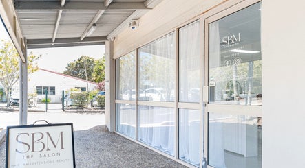 Front entrance of SBM The Salon at Boronia Heights, Queensland, AU, showcasing glass doors and salon signage.