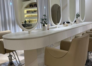 Modern beauty stations at Her Salon in Dubai, Dubai, AE featuring elegant mirrors and comfortable chairs.