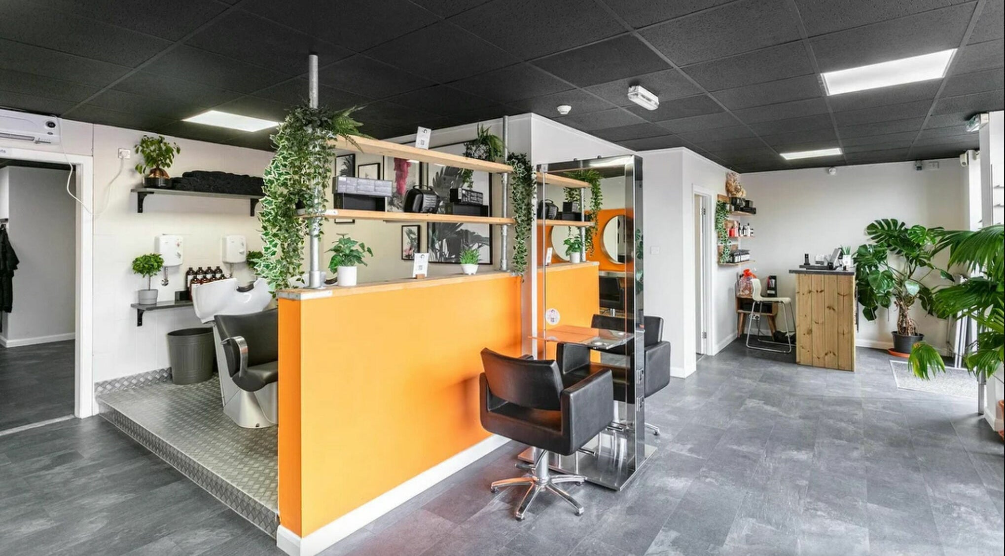 Modern salon interior at Ensō Hairdressing in Glasgow, Scotland, GB. Vibrant orange accents with stylish decor.