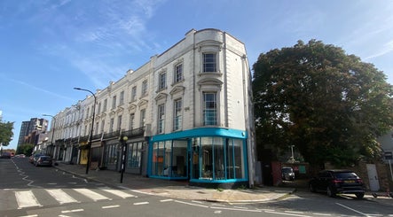 Street view of Blue Barbers in a classic building, London, England, GB, under a clear blue sky.