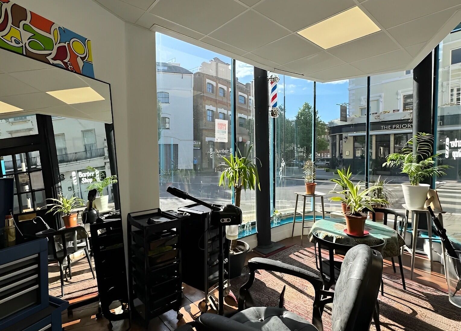 Interior of Blue Barbers in London, England, GB with large windows and potted plants.