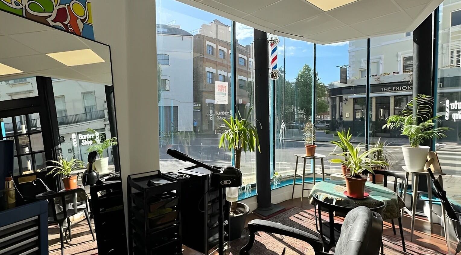 Interior of Blue Barbers in London, England, GB with large windows and potted plants.