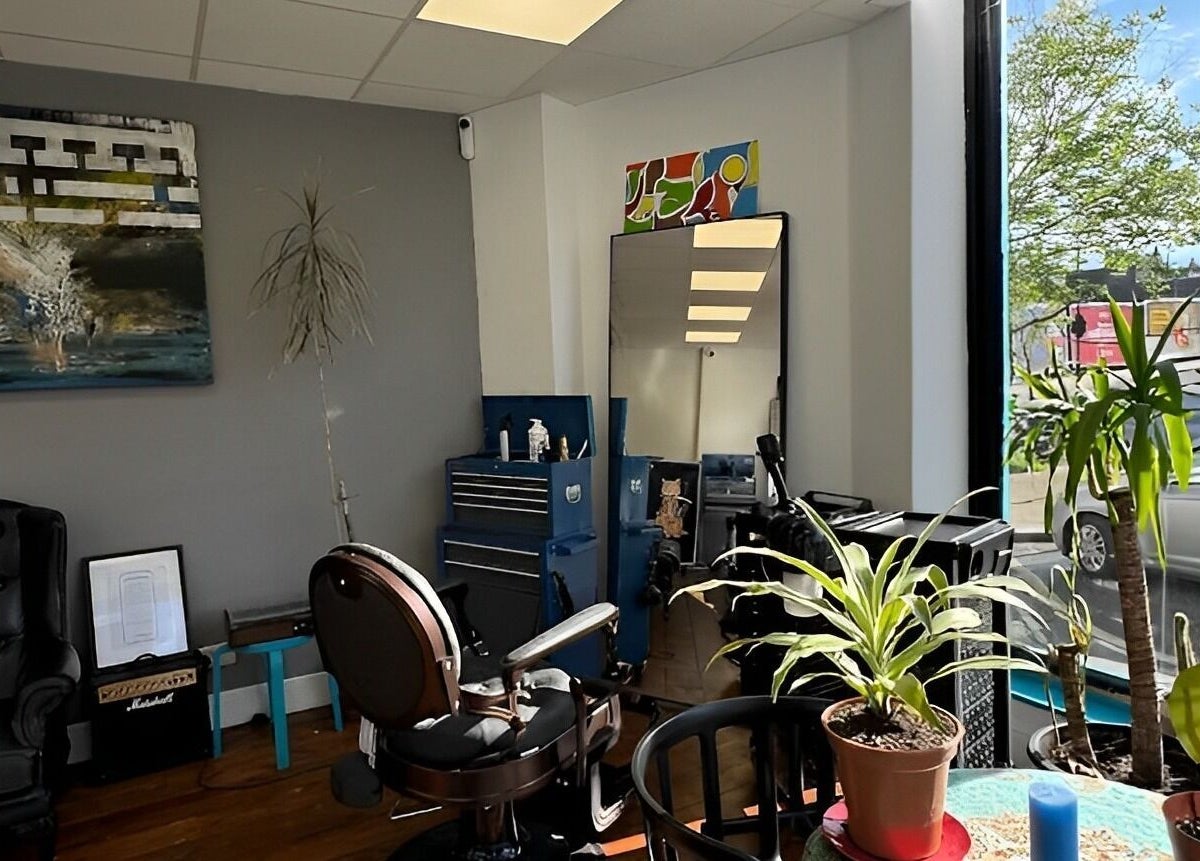 Interior of Blue Barbers, London, England, GB, showcasing stylish decor, large windows, and indoor plants.