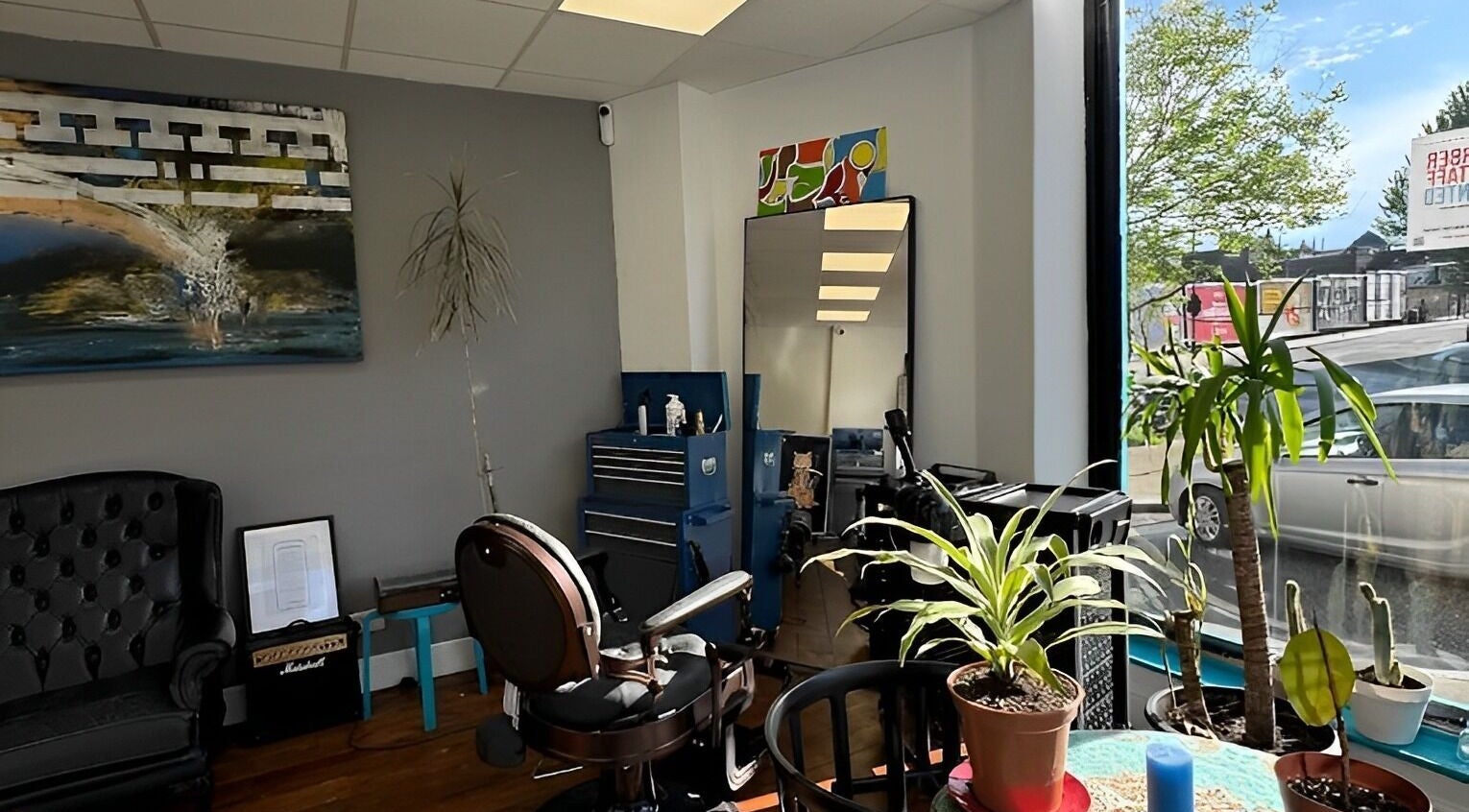 Interior of Blue Barbers, London, England, GB, showcasing stylish decor, large windows, and indoor plants.