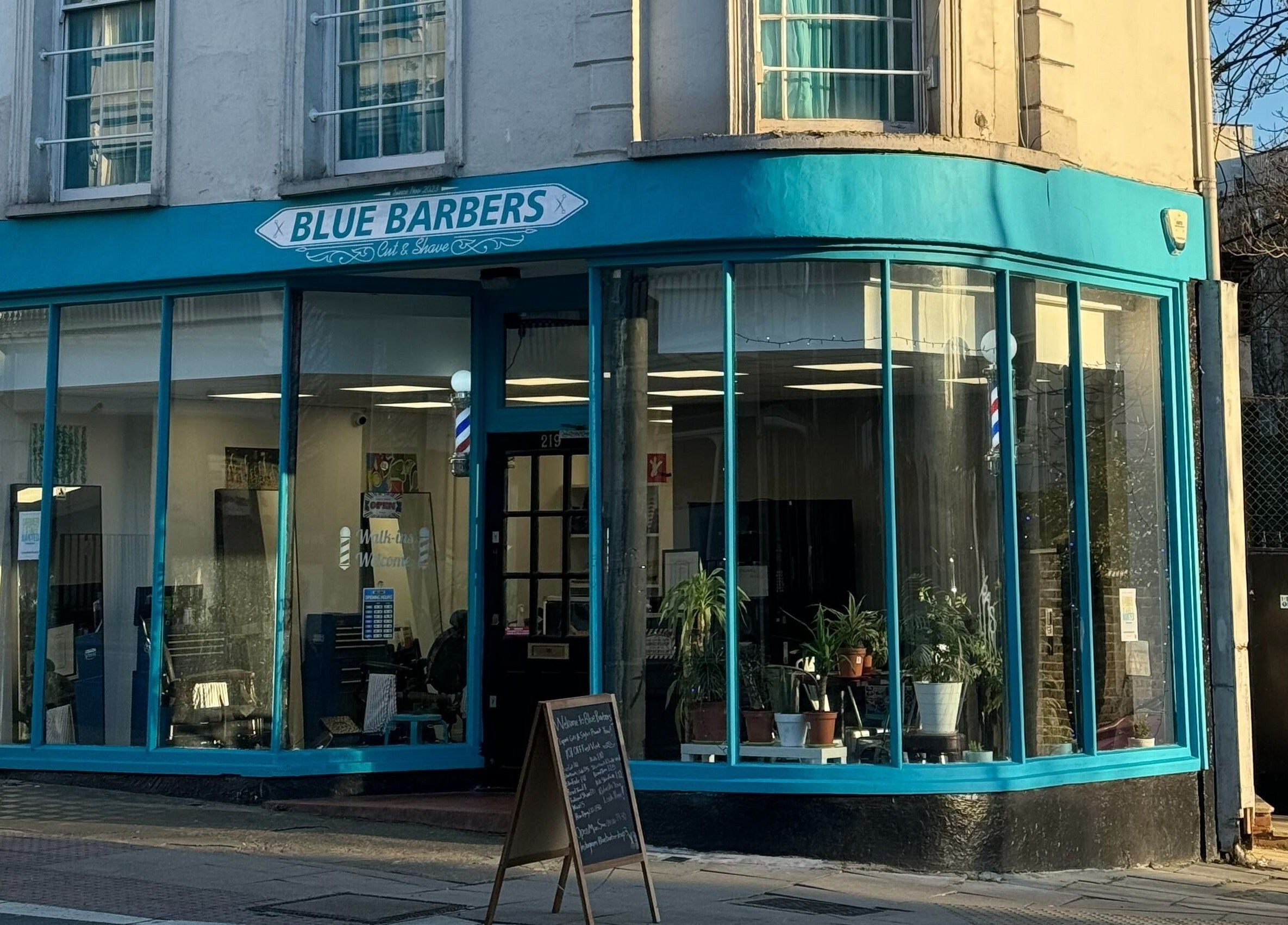 Front view of Blue Barbers with large windows in London, England, GB, showcasing a welcoming ambiance.