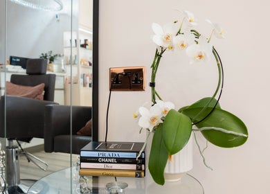 Elegant decor at NOGTI Nails Fitzrovia, London, England, GB with orchid and luxury books beside salon chair.