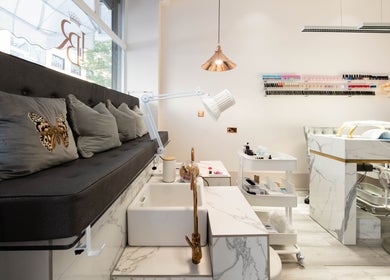 Interior of NOGTI Nails Fitzrovia in London, England, GB, featuring elegant marble decor and plush seating.