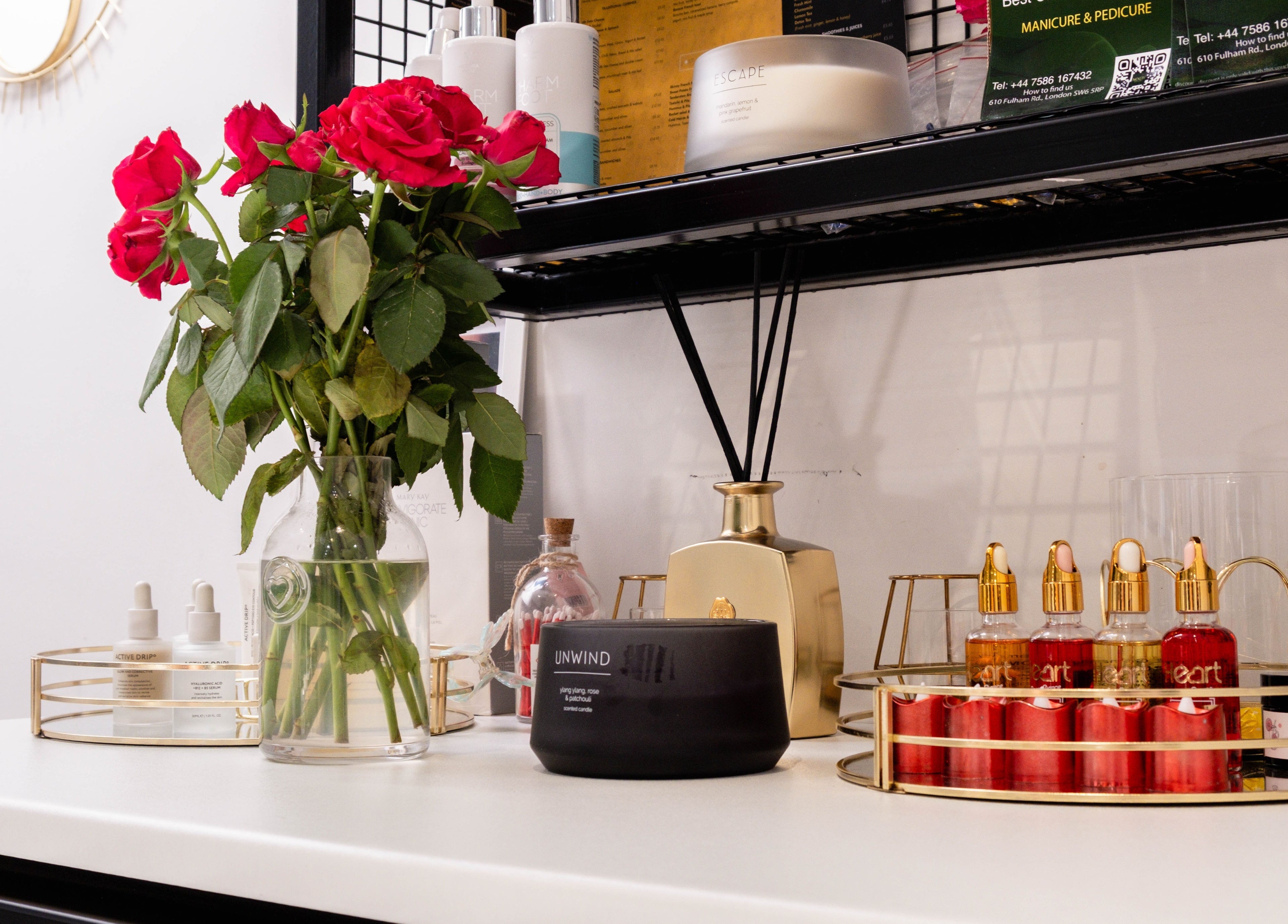 Stylish shelf at Nogti Nails Studio Fulham, London, England, GB with red roses and luxury beauty products.