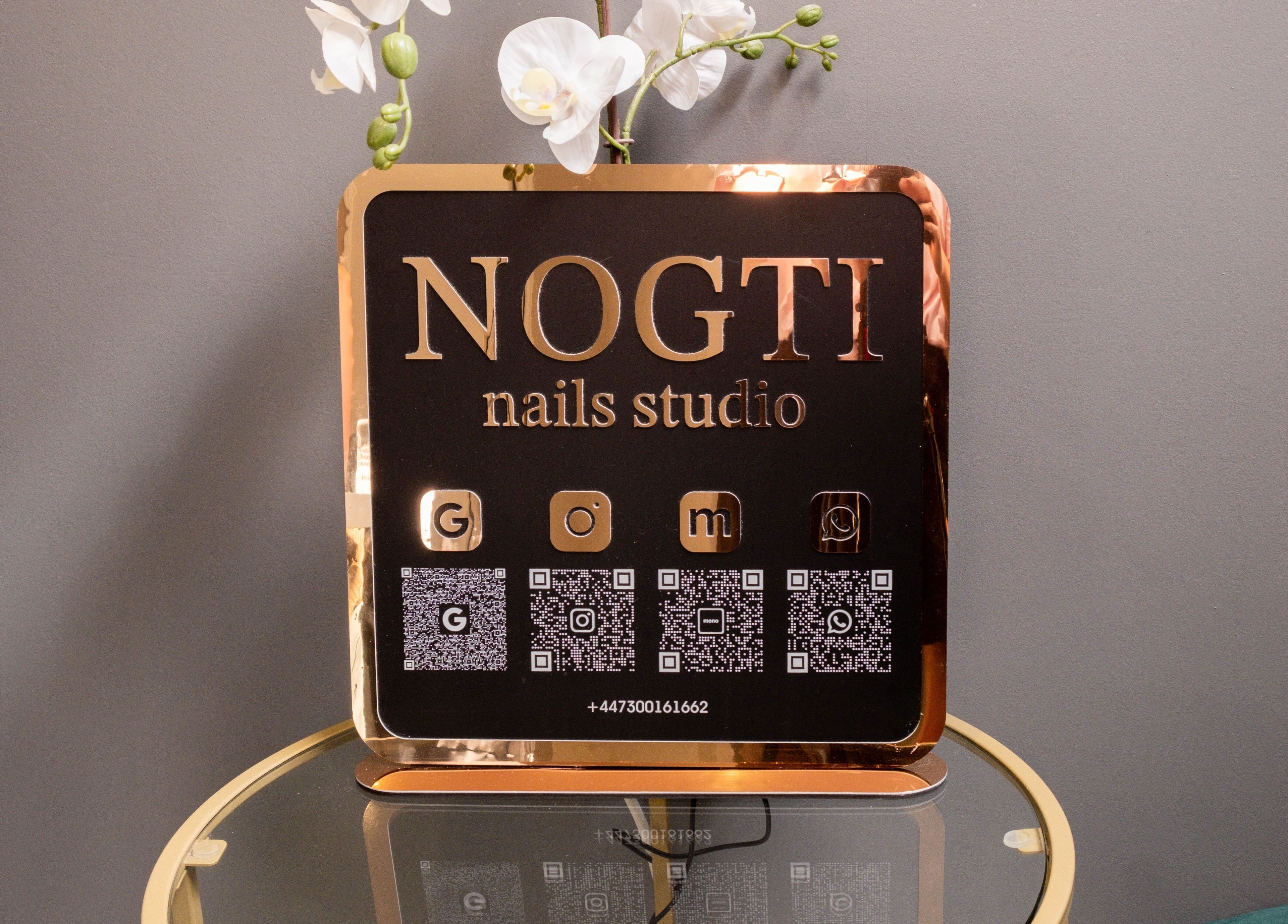 Stylish Nogti Nails Studio Fulham sign on a glass table in London, England, GB with floral decor.