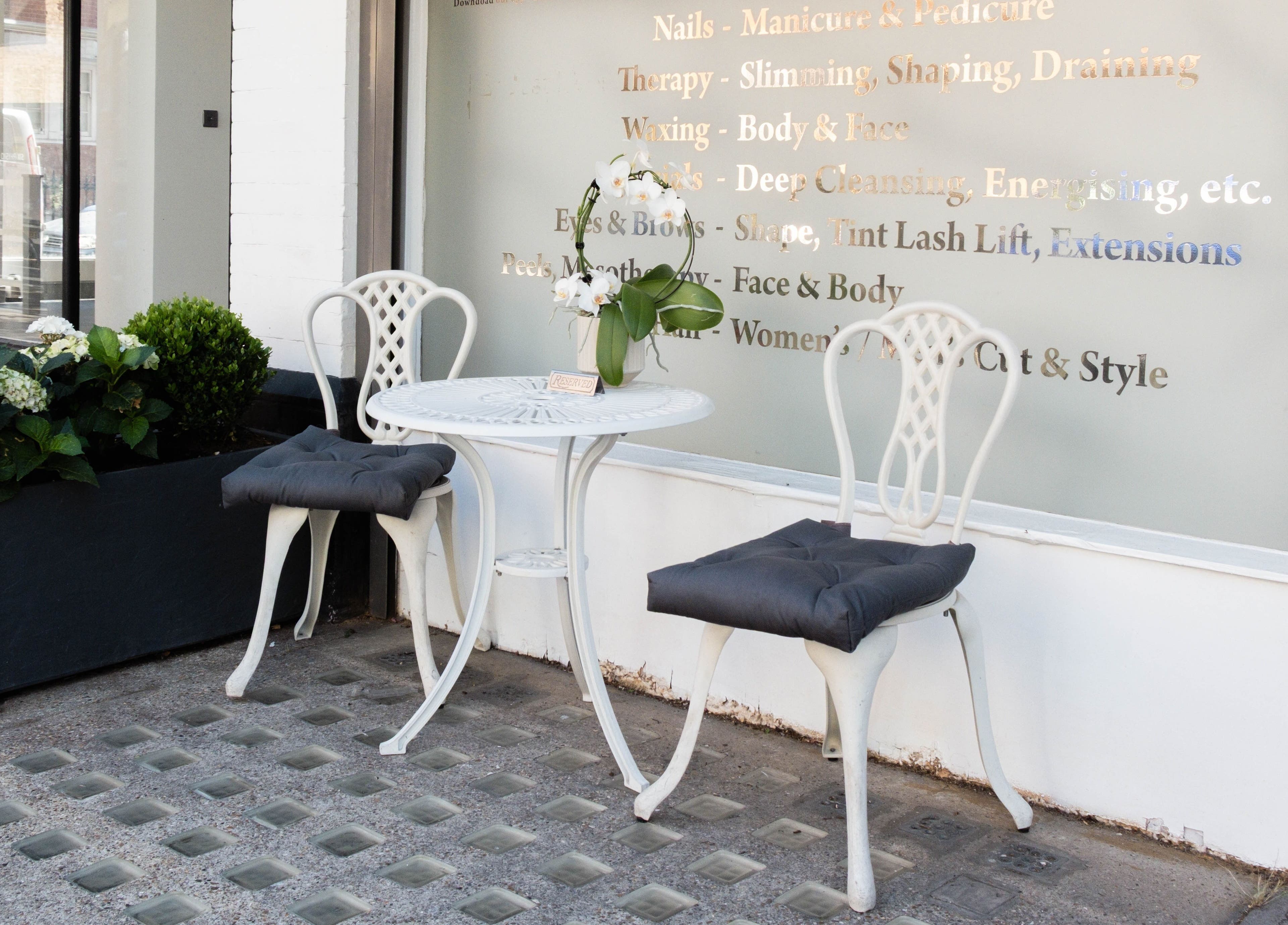 Stylish outdoor seating at NOGTI Nails Fitzrovia, London, England, GB, with elegant chairs and floral decor.