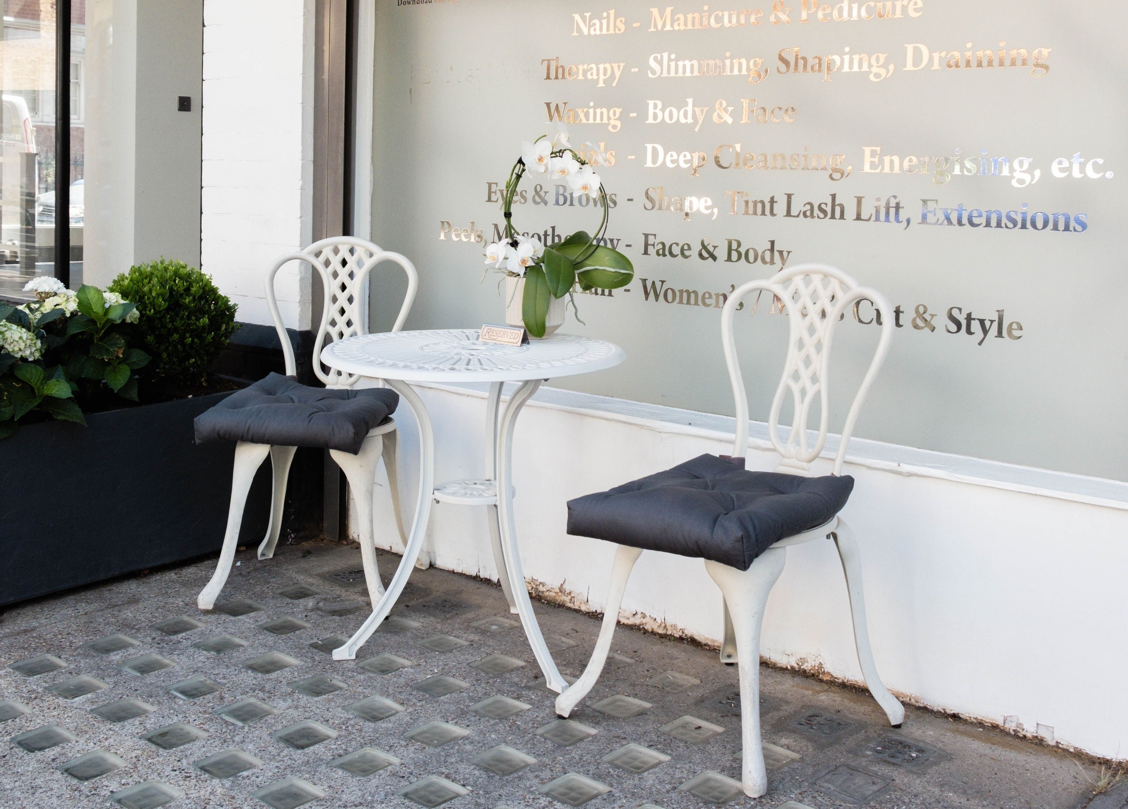 Stylish outdoor seating at NOGTI Nails Fitzrovia, London, England, GB, with elegant chairs and floral decor.
