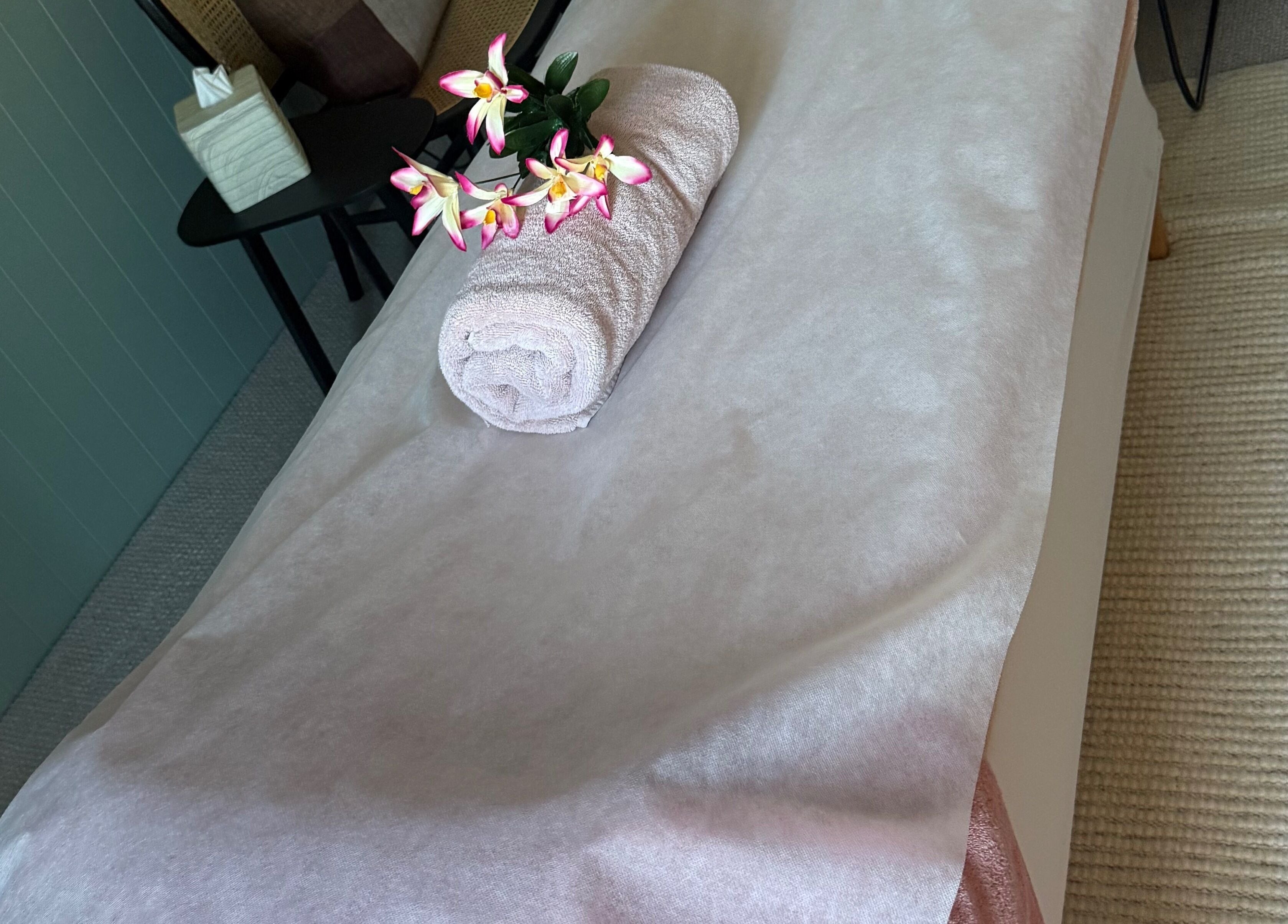 Rolled towel with flowers on spa table at Sophies Mobile Spa, Auckland, NZ.