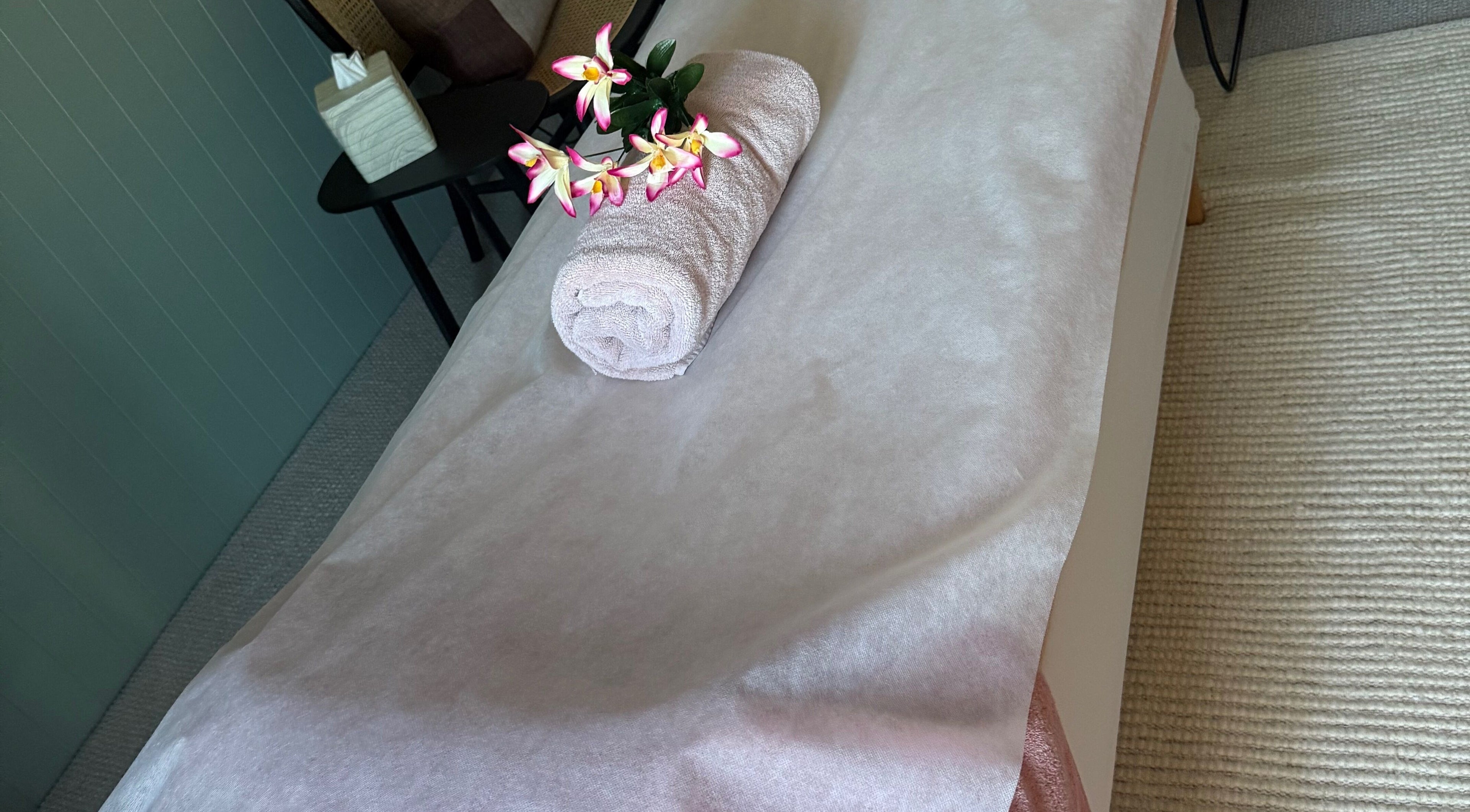 Rolled towel with flowers on spa table at Sophies Mobile Spa, Auckland, NZ.