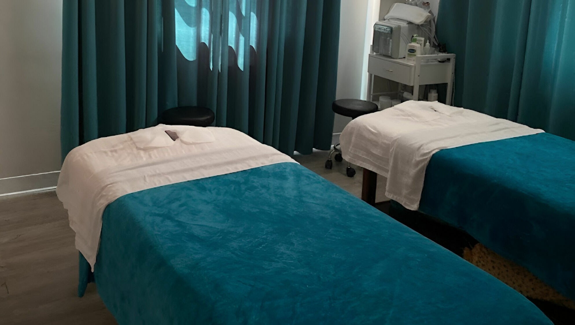 Twin massage beds with teal covers at Unique Massage Spa in Fairfax, Virginia, US, offering tranquil treatments.