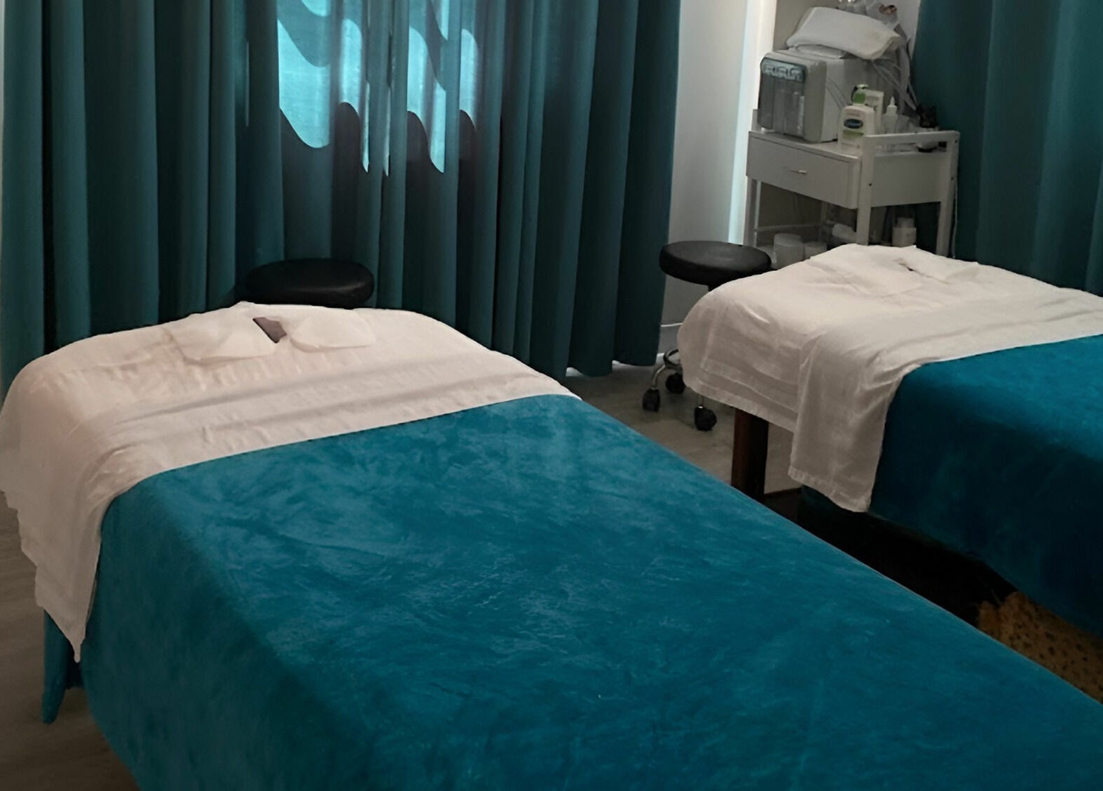 Twin massage beds with teal covers at Unique Massage Spa in Fairfax, Virginia, US, offering tranquil treatments.