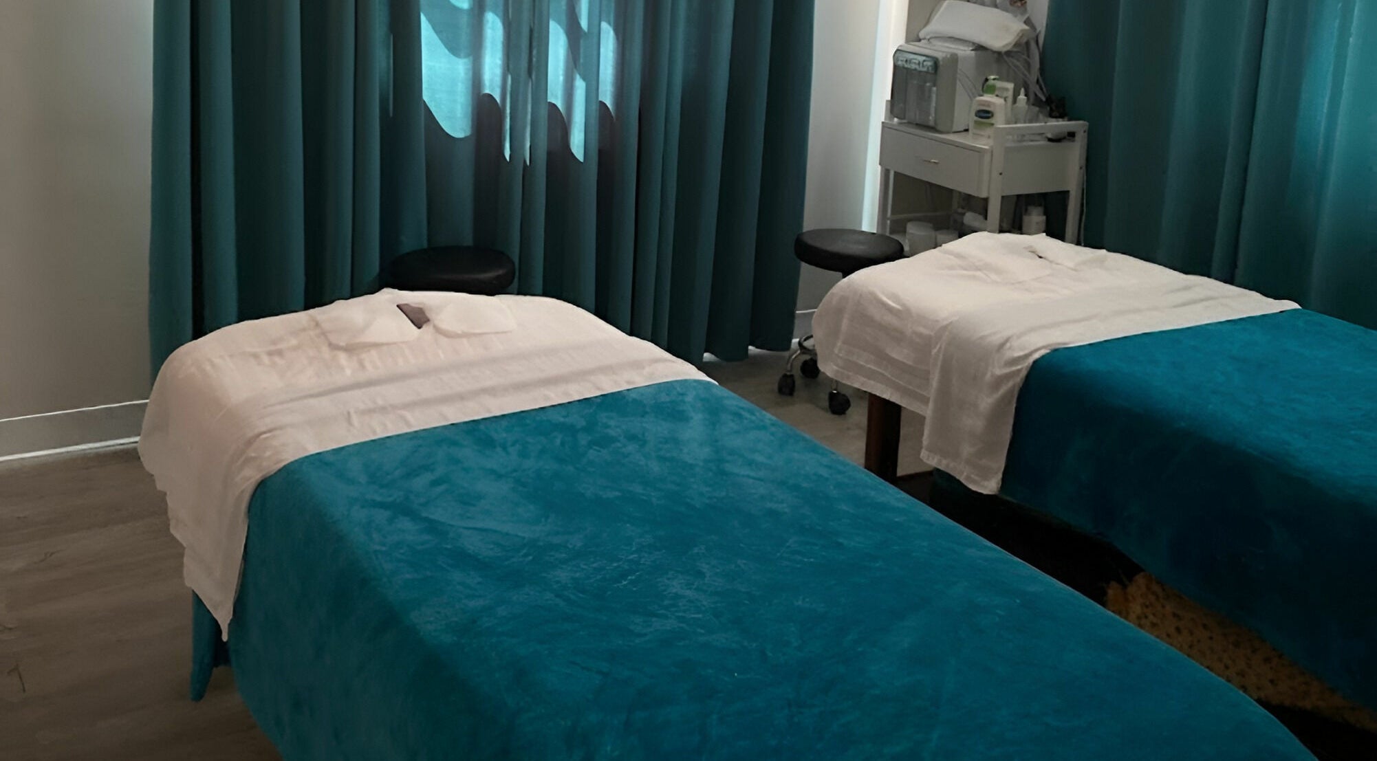 Twin massage beds with teal covers at Unique Massage Spa in Fairfax, Virginia, US, offering tranquil treatments.