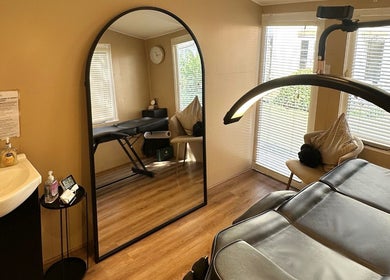 Relaxing treatment room at The Glow Hub, Black Notley, England, featuring a massage table and large mirror.