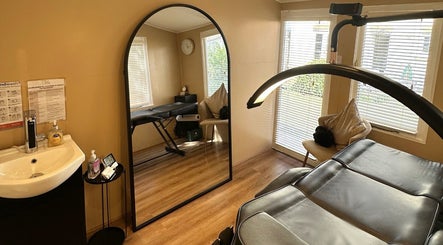 Relaxing treatment room at The Glow Hub, Black Notley, England, featuring a massage table and large mirror.