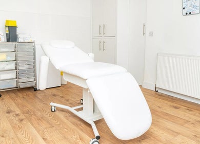 Relaxing treatment room at Oh So Glow, Halifax, England, GB, with a cozy white bed and storage unit.