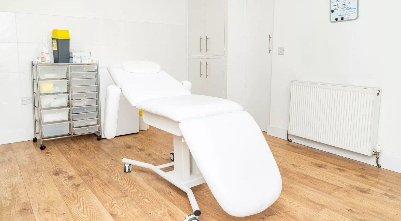 Relaxing treatment room at Oh So Glow, Halifax, England, GB, with a cozy white bed and storage unit.
