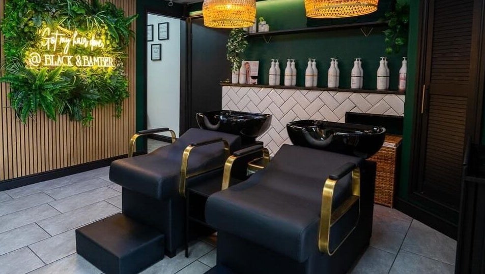 Elegant salon setup at Black & Bamber, Hull, England, GB, featuring stylish black wash stations and lush greenery.