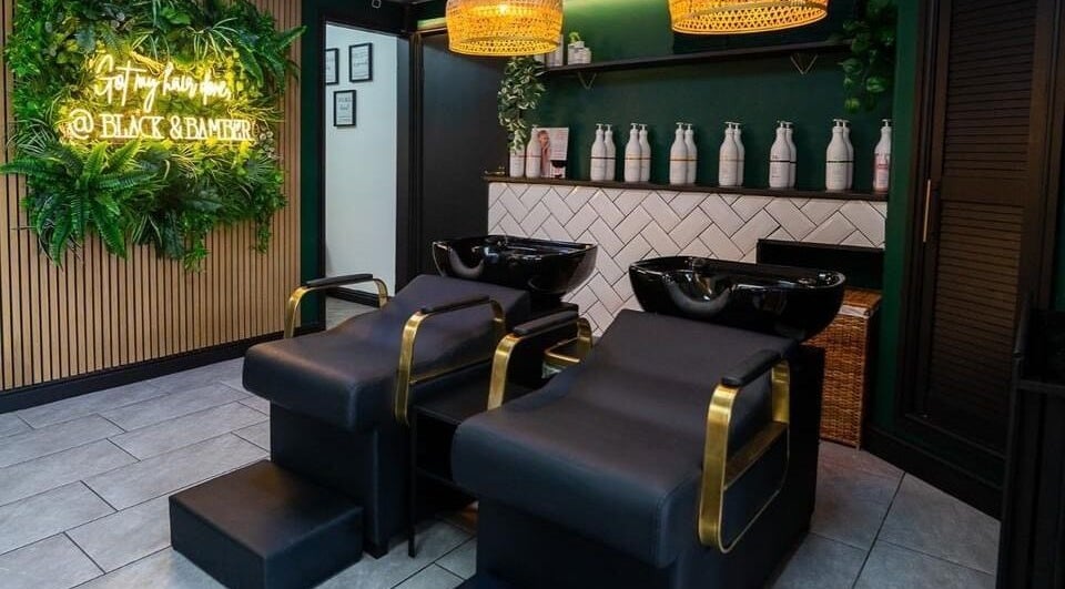 Elegant salon setup at Black & Bamber, Hull, England, GB, featuring stylish black wash stations and lush greenery.