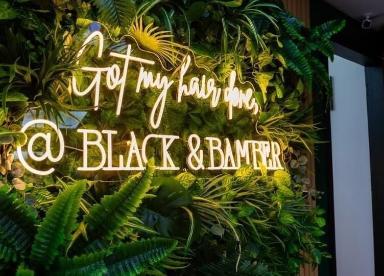 Lush green wall with neon sign 'Got my hair done @ Black & Bamber', Hull, England, GB.