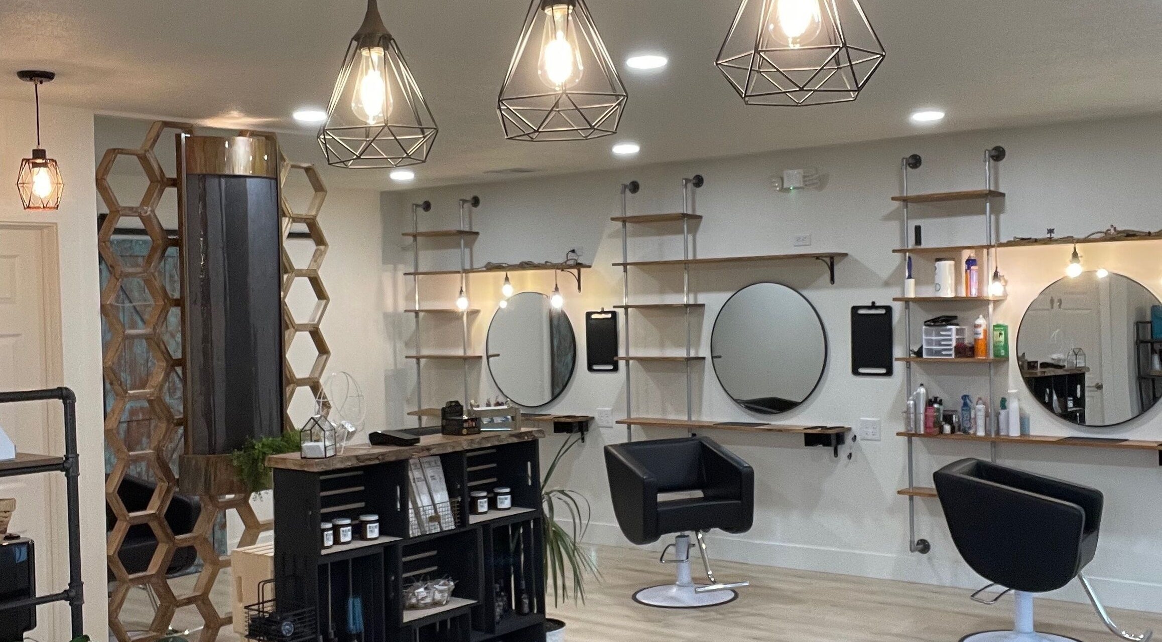 Modern interior of The Copper Moss salon in Haysville, Kansas, US, featuring stylish chairs and geometric lights.