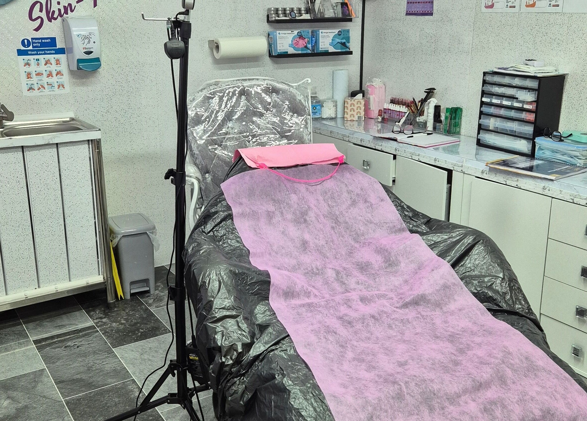 Skin-Finity treatment room with pink draped chair in Aylesham, England, GB, showcasing a clean, professional setup.